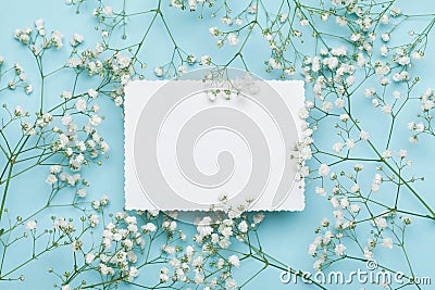 Wedding mockup with white paper list and flowers gypsophila on blue table from above. Beautiful floral pattern. Flat lay style. Stock Photo