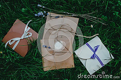 Wedding or party decorative envelopes lie on the green grass. Ivory, brown and violet colours. Strings and lavender. Rustic Stock Photo