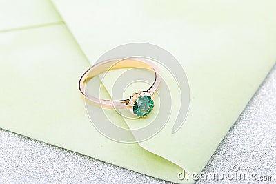 Wedding ring with emerald green gemstone on greenery envelope Stock Photo
