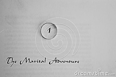 A wedding ring on a page that states the marital adventure Stock Photo