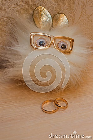 Wedding ring. Two gold vintage rings of the bride and groom and an unusual white toy with glasses Stock Photo