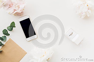 Wedding ring in white gift box on background of flowers and phone. top view Stock Photo