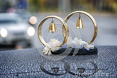 Wedding rings with bells in drops of rain on the roof of the car Stock Photo