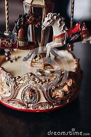 Wedding rings lie on a toy carousel with little horses Stock Photo