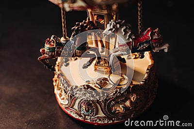 Wedding rings lie on a toy carousel with little horses Stock Photo