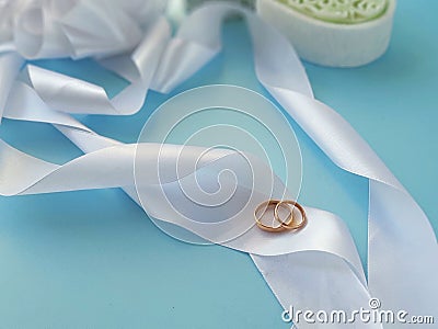 Wedding rings on silk ribbons on blue background. Stock Photo