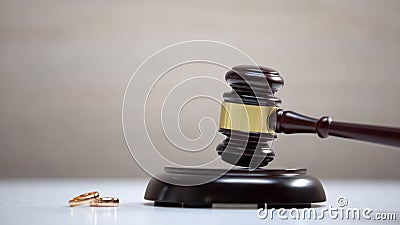 Wedding rings on table, gavel standing on sound block, divorce procedure, court Stock Photo