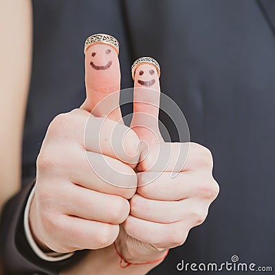 Wedding rings on their fingers painted with the bride and groom, funny little people Stock Photo