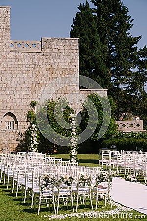 Wedding semi-arch stands near a brick wall in the garden in front of rows of chairs Stock Photo