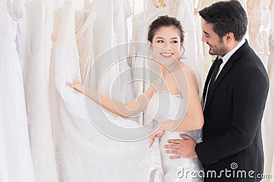 Wedding shopping lifestyle Concept, beautiful Asian girl show dress to groom making decision for wedding ceremony, man help woman Stock Photo