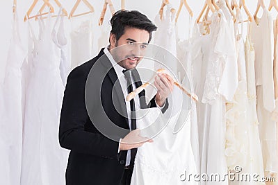 Wedding shopping lifestyle Concept, handsome groom help bride to choose beautiful wedding in fitting room studio, happy couple Stock Photo