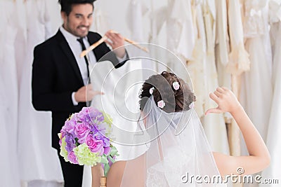 Wedding shopping lifestyle Concept, handsome groom help bride to choose beautiful wedding in fitting room studio, happy couple Stock Photo