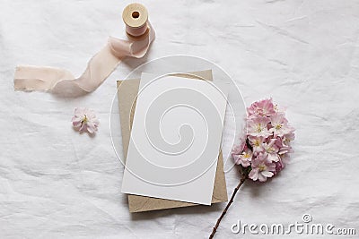 Wedding stationery mock-up scene. Blank vertical greeting card, envelope on linen tablecloth background with pink Stock Photo