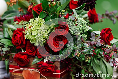 Wedding table decor: flowers composition with roses, berries, herbs and greenery standing in wooden box. Bridal details and decora Stock Photo