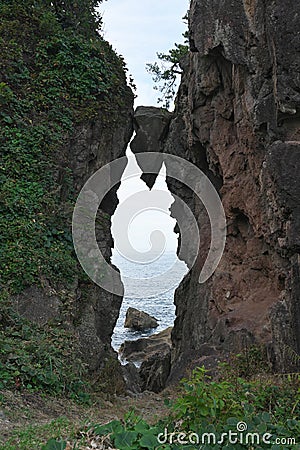 A wedge-shaped rock between two giant rocks or Benkei no Hasamiiwa at Sado island, Japan Stock Photo