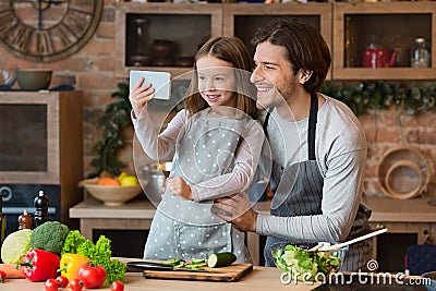 Weekend With Daddy. Cheerful Father And Little Daughter Taking Selfie In Kitchen Stock Photo