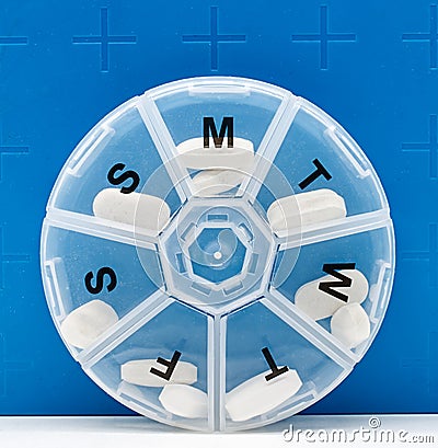 Weekly medicine dispenser. Pills in a daily medicine dose box on blue background Stock Photo