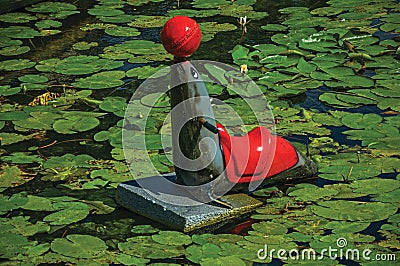 Seal statue with ball in the nose on the canal water with aquatic plants at Weesp. Editorial Stock Photo