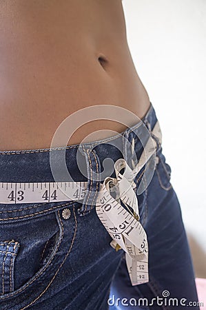 Weight-loss concept with young Indian female wearing tape measure as a belt Stock Photo