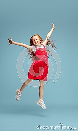 Happy redhair girl isolated on blue studio background. Looks happy, cheerful, sincere. Copyspace. Childhood, education Stock Photo