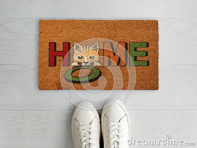 Welcome Home Coir entry designer doormat with white sneaker shoes Stock Photo