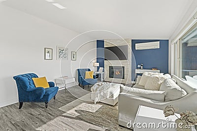 Welcoming living room with a blue accent wall, white faux fur pillows and a modern fireplace Stock Photo