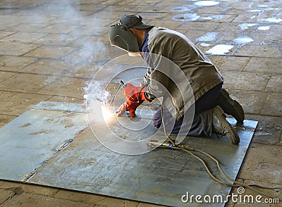 Welder in factory. A worker welds a steel sheet Stock Photo