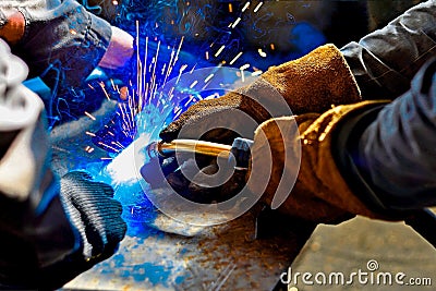 A welder in protective gloves produces a metal connection by electrical welding Stock Photo
