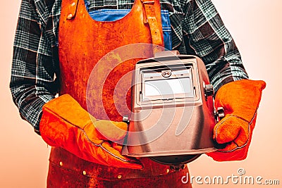 Welder in protective suit, gloves, holding a welding mask, Close-up, Fiery colors Stock Photo