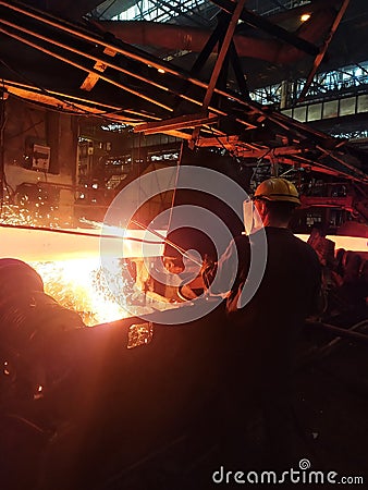 Welder in protective uniforms and masks at the pipe mill. metallurgy industry Stock Photo