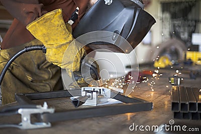 Welder welding steel stool support to each other. Stock Photo