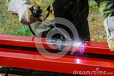 Welder welds steel closed profile. Arc welding outdoors Stock Photo