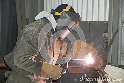 A welder welds technological pipelines with manual arc welding for an oil refinery in Russia. Welded joint Stock Photo