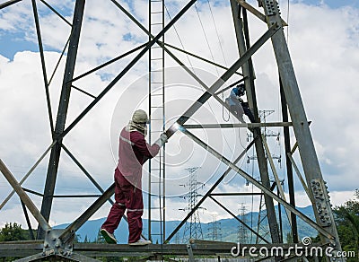 Welder work at high Electric high voltage pole 230 Kv. Editorial Stock Photo