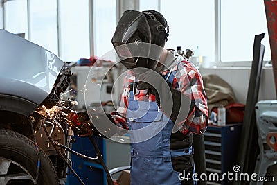 Welder in work overalls works in a car workshop Stock Photo