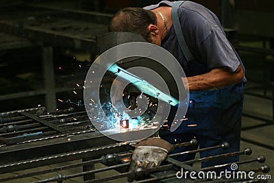 Welder in a workshop making a fence Editorial Stock Photo