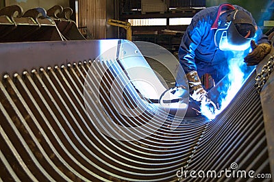 Welder in a factory, repairing a steel blade of a bulldozer Stock Photo