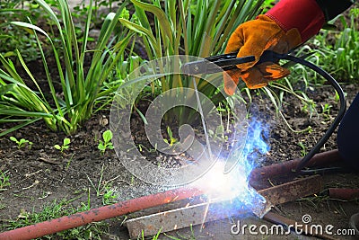 Welding work on the street. Welder cooks metall parts on the ground Stock Photo