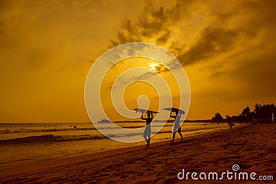 WELIGAMA, SRI LANKA - JANUARY 12 2017: Unidentified couple surfing on sunset on Weligama beach on the coast of Indian ocean - is Editorial Stock Photo