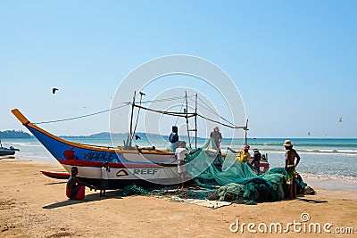 Group local of fishermen reviewing and folding fishing nets near the traditional wooden boat Editorial Stock Photo