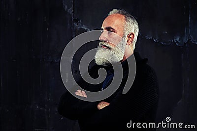 A well-built man with grey beard standing and folded arms looking narrowly Stock Photo