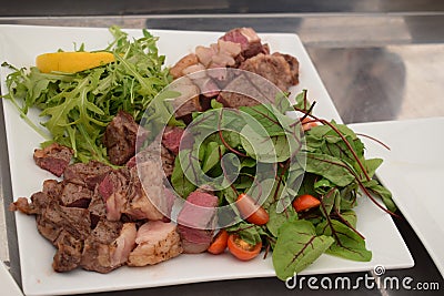 Well-cooked meat with herbs and tomatoes on a plate Stock Photo