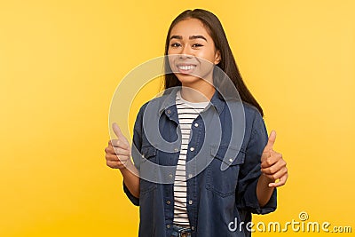 Well done, awesome result! Portrait of happy girl in denim shirt showing thumbs up, gesturing like and smiling Stock Photo