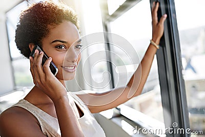 Well double your earnings for you. A young businesswoman talking on her cellphone while standing by her office window. Stock Photo