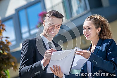 Well-dressed male client signing the documents, female broker looking pleased Stock Photo