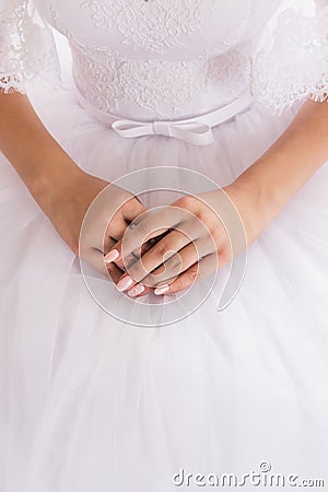 Well-groomed hands of the bride with a beautiful manicure are on a white wedding dress Stock Photo