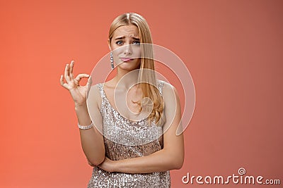 Well not bad. Hesitant unsure cute stylish wealthy blond girlfriend in silver dress frowning cringing doubtful show okay Stock Photo