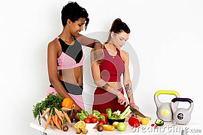 Lovely fitness vegetarian ladies cutting vegetables on table Isolated on white background. Stock Photo