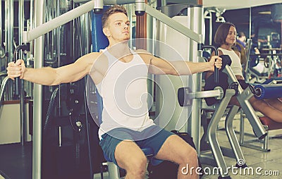 Well trained man using pec deck gym machinery indoors Stock Photo