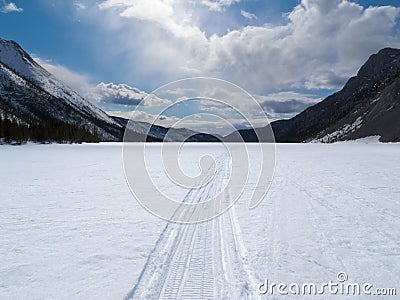 Well used winter trail on frozen mountain lake Stock Photo